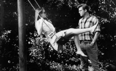 Still in the park from the movie Crush where Alicia Silverstone is on a swing while Cary Elwes is standing in front of her. 